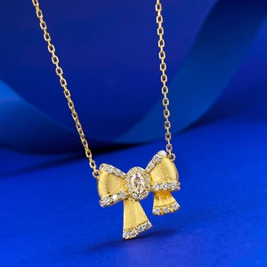Elegant gold bow necklace with brushed texture and marquise-cut crystal pendant