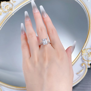 Close-up of emerald-cut crystal ring with paved diamonds on a hand, silver-white tone