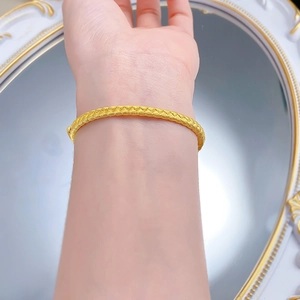 Close-up of golden woven wheat ear bracelet on wrist with elegant vintage mirror backdrop