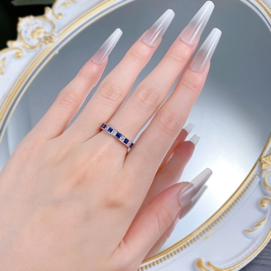 Détail d'une bague dorée avec oxydes de zirconium bleus et blancs en serti rail chic