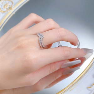 Close-up of a silver wave-shaped V-ring set with baguette-cut zircons on a finger