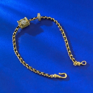 Makroansicht von geflochtenem schwarzem Armband mit Goldperlen und Kleeblatt-Detail