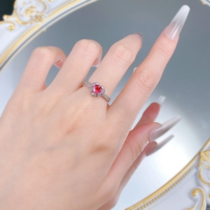 Close-up of heart-shaped red ruby ring with pavé diamond setting worn on hand