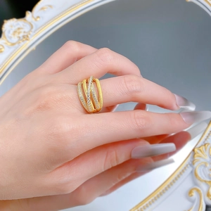 Close-up of interweaving gold brushed bands and pavé diamond rings on a finger