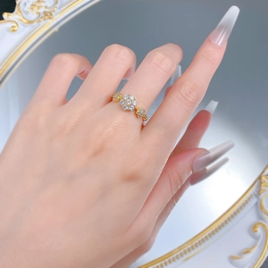 Detail of a gold floral ring with sparkling zircon stones worn on a finger