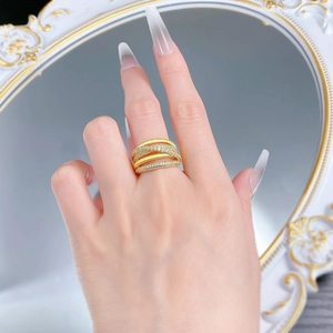 Close-up of a gold-plated multi-layer crisscross ring with pavé-set stones on a model