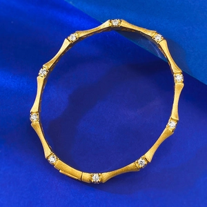Detail shot of gold brushed bamboo bangle featuring small sparkling inlaid round gemstones