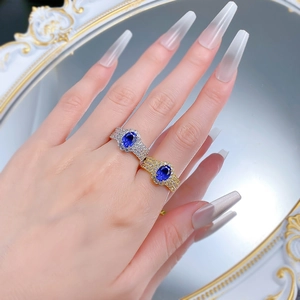 Close-up of model wearing sapphire rings with pavé diamonds in gold and silver finish