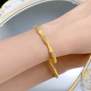Detail of gold bamboo bracelet with matte texture and sparkling stones on wrist