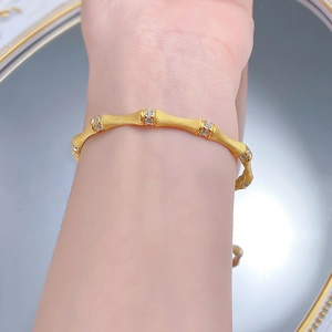Detail of matte gold bamboo link bracelet with zircon accents on a female wrist