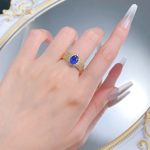 Luxurious gold ring with oval blue sapphire and pavé diamonds worn on hand