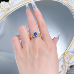 Close-up of an oval blue sapphire ring with halo diamonds on a woman's finger