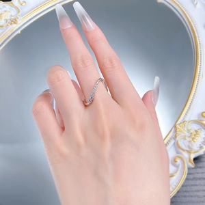 Close-up of S-shaped wavy silver ring with sparkling cubic zirconia on a female finger