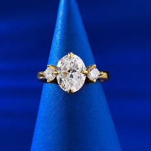 Detailed macro view of 7x9 oval cut stone with round side stones in gold claw setting