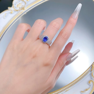 Macro shot of oval blue sapphire ring with sparkling diamond halo on silver band