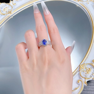 Close-up of S925 silver ring with oval blue sapphire and pavé diamonds worn on hand