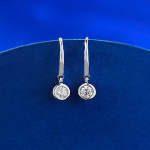 Macro detail of silver drop earrings with round bezel-set zircon on French hooks