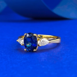 Classic oval blue sapphire ring with pear-shaped side stones on a gold-plated band