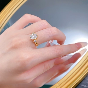 Detailed view of an oval-cut diamond ring on a hand with gold plated band