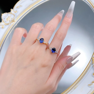 Detail of oval blue sapphire rings in gold and silver finish with pear side stones