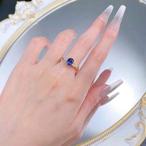 Detail of an oval blue sapphire ring on gold band with marquise side diamonds