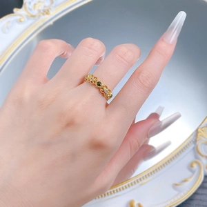 Détail d'une bague vintage dorée avec émeraude et zircons sur fond de miroir chic