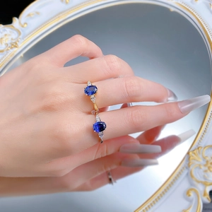 Macro shot of oval blue sapphire ring with side stones reflected on a white mirror