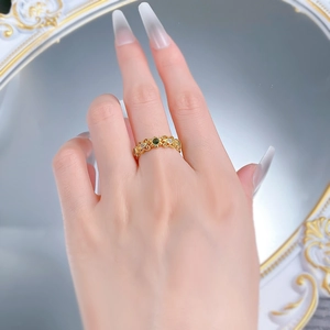 Détail d'une bague vintage en dentelle dorée avec pierre verte et diamants sur modèle