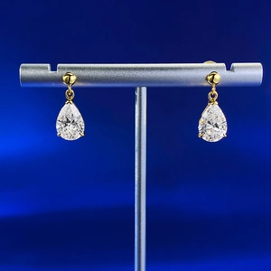 Detailed macro view of S925 silver pear-cut teardrop earrings on a gold plating display