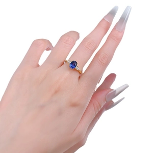 Elegant 18K gold ring with oval blue sapphire and marquise side stones on a model hand