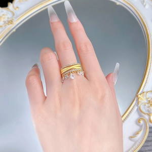 Detail of gold multi-layered ring with sparkling tassels on hand against mirror