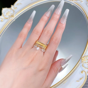 Macro shot of gold-plated multi-layer ring with sparkling white diamonds and teardrop charms