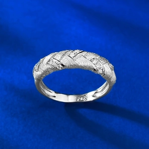 Macro detail of S925 sterling silver braided ring with zircon inlay on blue fabric
