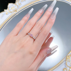 Gros plan d'une bague ovale avec pierre rose et anneau en argent pavé porté à la main