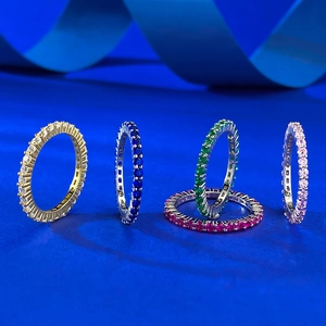 Detail of five S925 silver eternity rings with colorful zircon stones on blue ribbon
