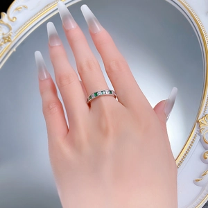 Detail of silver eternity ring featuring princess cut emerald and white zirconia stones