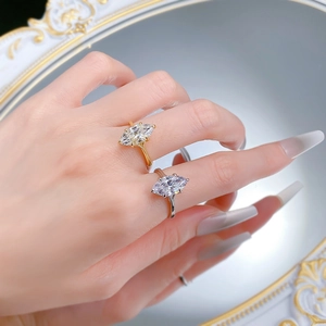 Close-up of gold and silver marquise-cut solitaire rings on fingers in front of a mirror