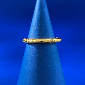 Detailed view of gold snake scale ring with diamonds on a blue conical stand