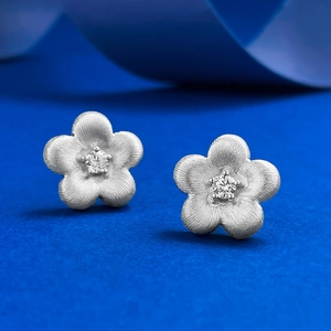 Detailed macro view of S925 silver flower stud earrings with brushed finish and zircon center
