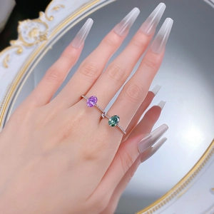 Close-up of 925 sterling silver rings featuring green and purple oval gemstones on hand