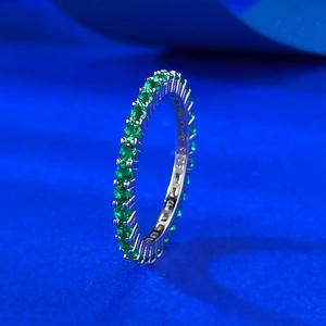 Macro shot of S925 sterling silver eternity ring with green gemstones on blue background