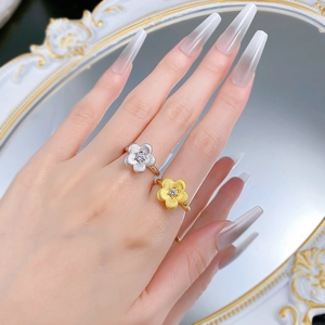 Detail of gold and silver flower rings with matte brushed finish and zircon center