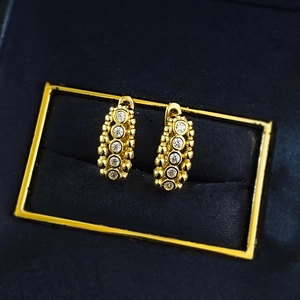 Detail of gold huggie earrings featuring pave set white cubic zirconia and beaded edges