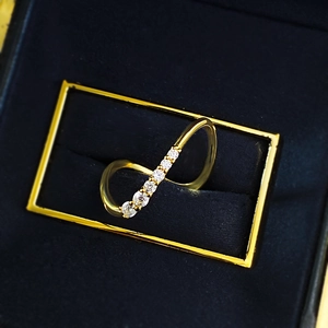 Close-up of golden wavy S925 silver ring with seven pavé zircons in a black jewelry box