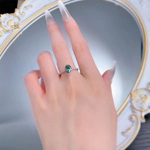Close-up of a 925 silver ring featuring an oval green gemstone and pavé diamonds