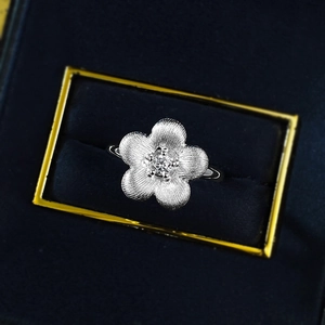 S925 silver flower ring with brushed texture and center crystal in a blue velvet box