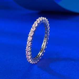 Macro shot of silver eternity ring with pavé-set pink round-cut crystals on blue background