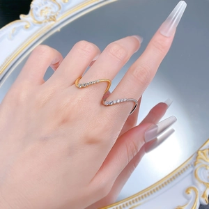 Close-up of gold and silver wavy open rings with sparkling zircons worn by a model