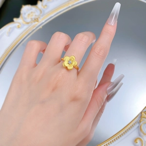 Macro shot of gold-plated flower ring with brushed texture and sparkling center diamond