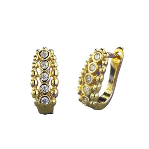 Gold U-shaped huggie earrings with five white zircons and beaded edge detail
